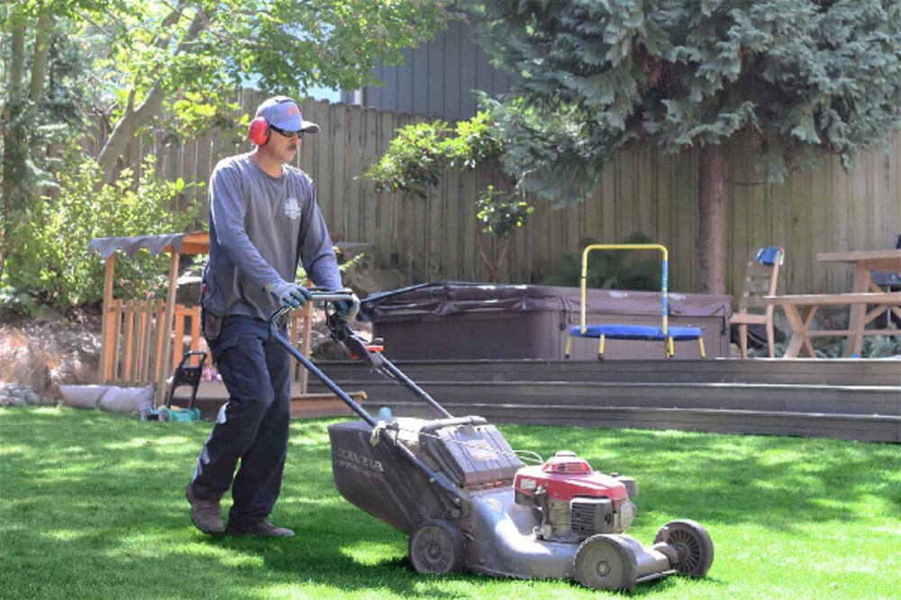 Crew member mowing the lawn during a yard clean up